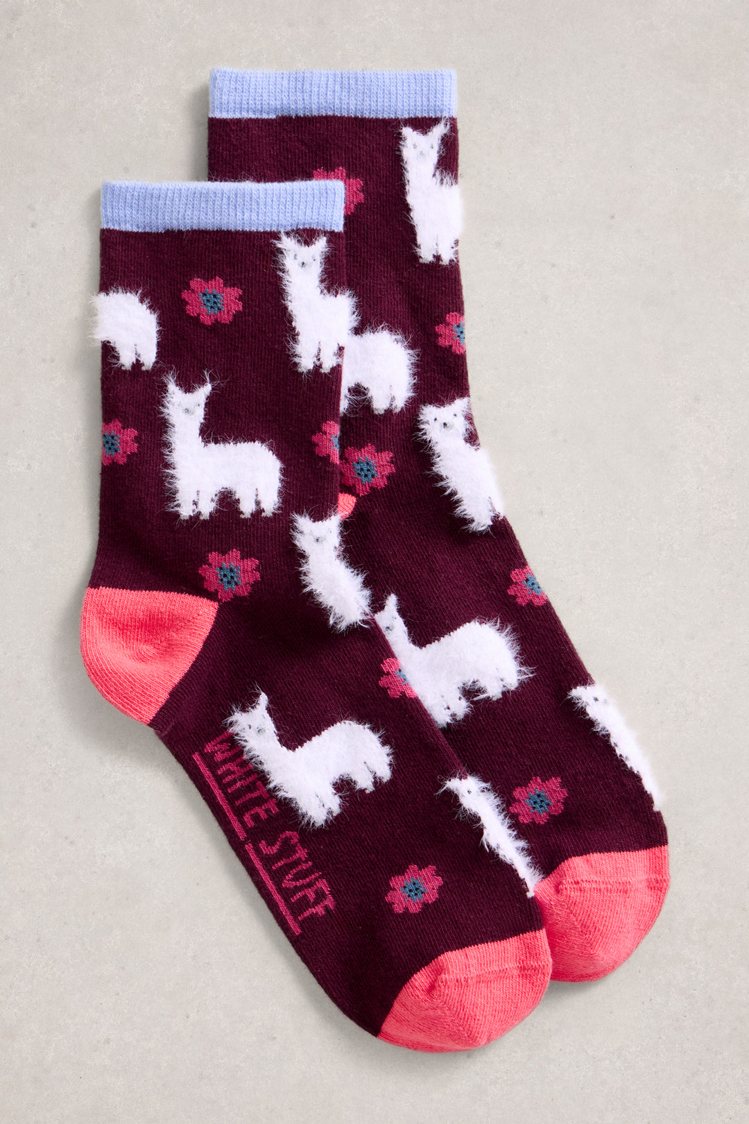 Maroon socks with white llama designs and pink accents on a beige background