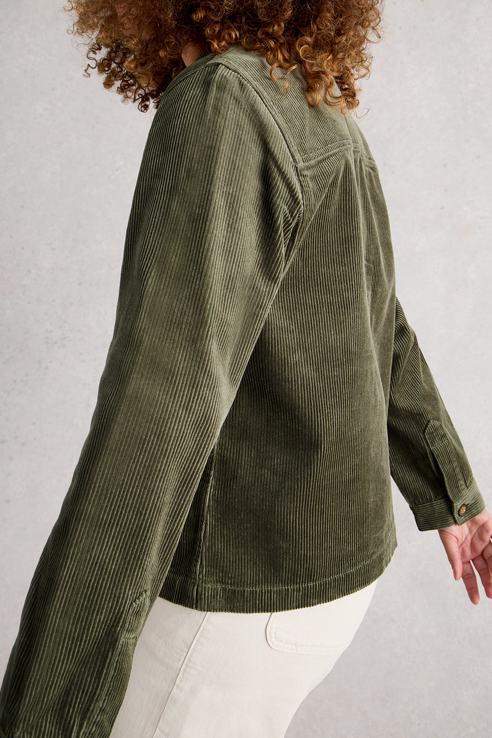 Person wearing a green corduroy jacket against a light gray background