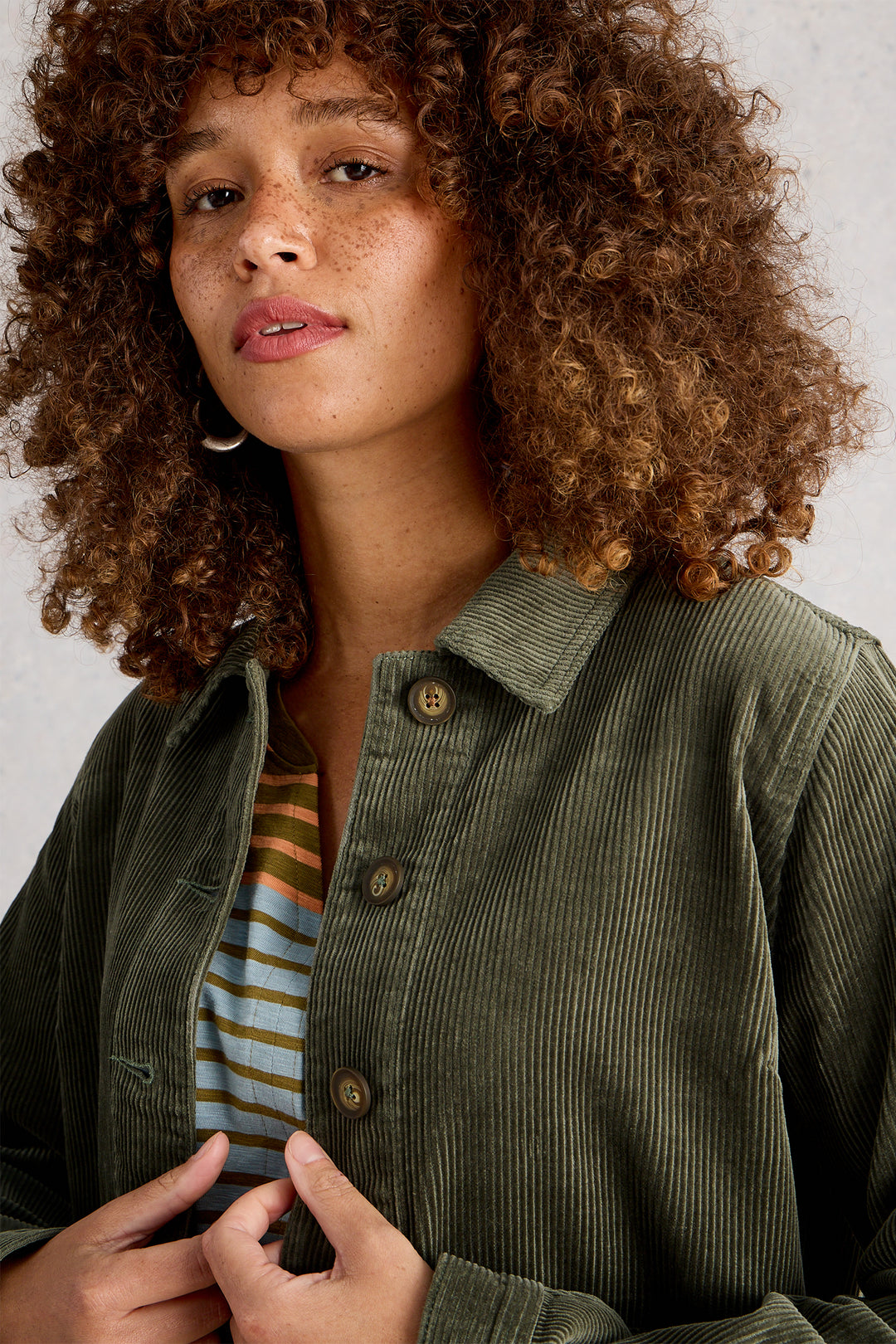 Woman wearing a green corduroy jacket against a neutral background