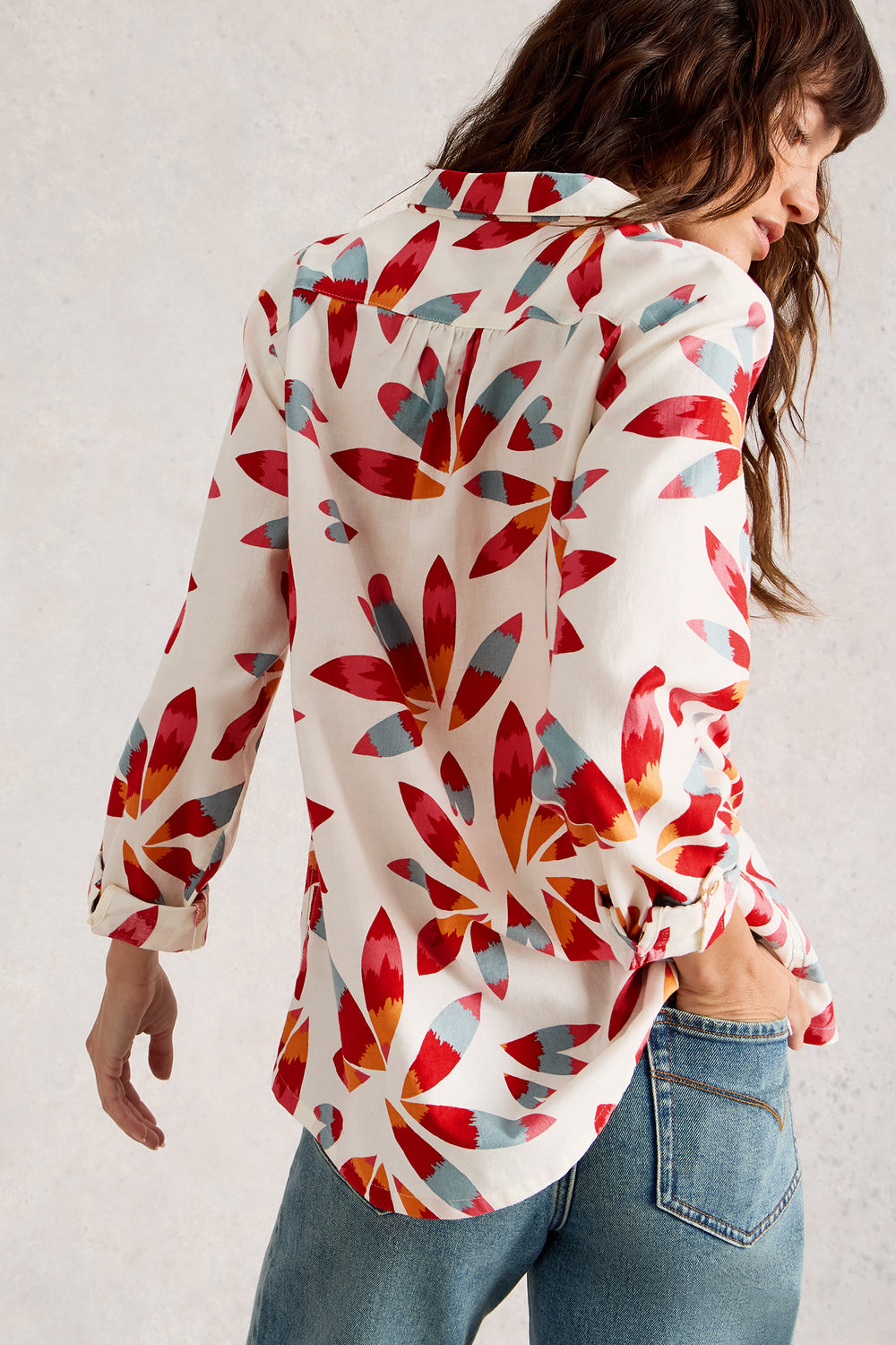 Woman wearing a colorful floral patterned shirt against a plain background