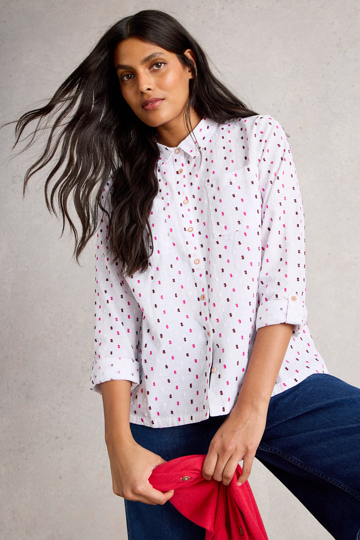 Woman wearing a white blouse with red patterns against a gray background