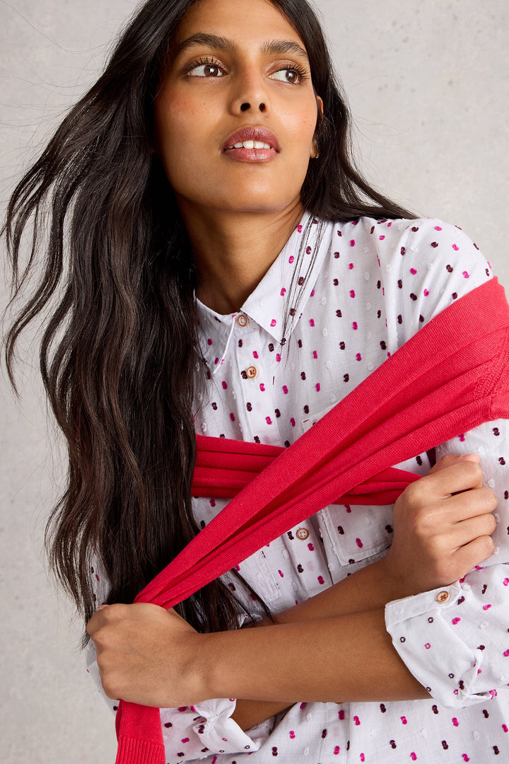 Woman holding a red scarf against a neutral background