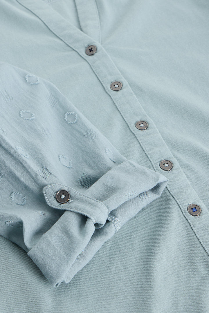 Close-up of a light blue shirt with buttons and rolled-up sleeve
