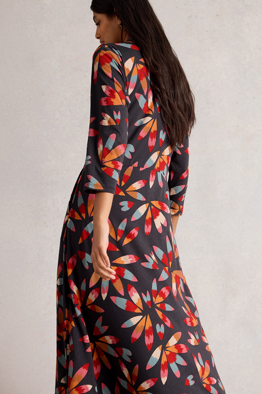 Woman wearing a colorful floral dress with a plain background