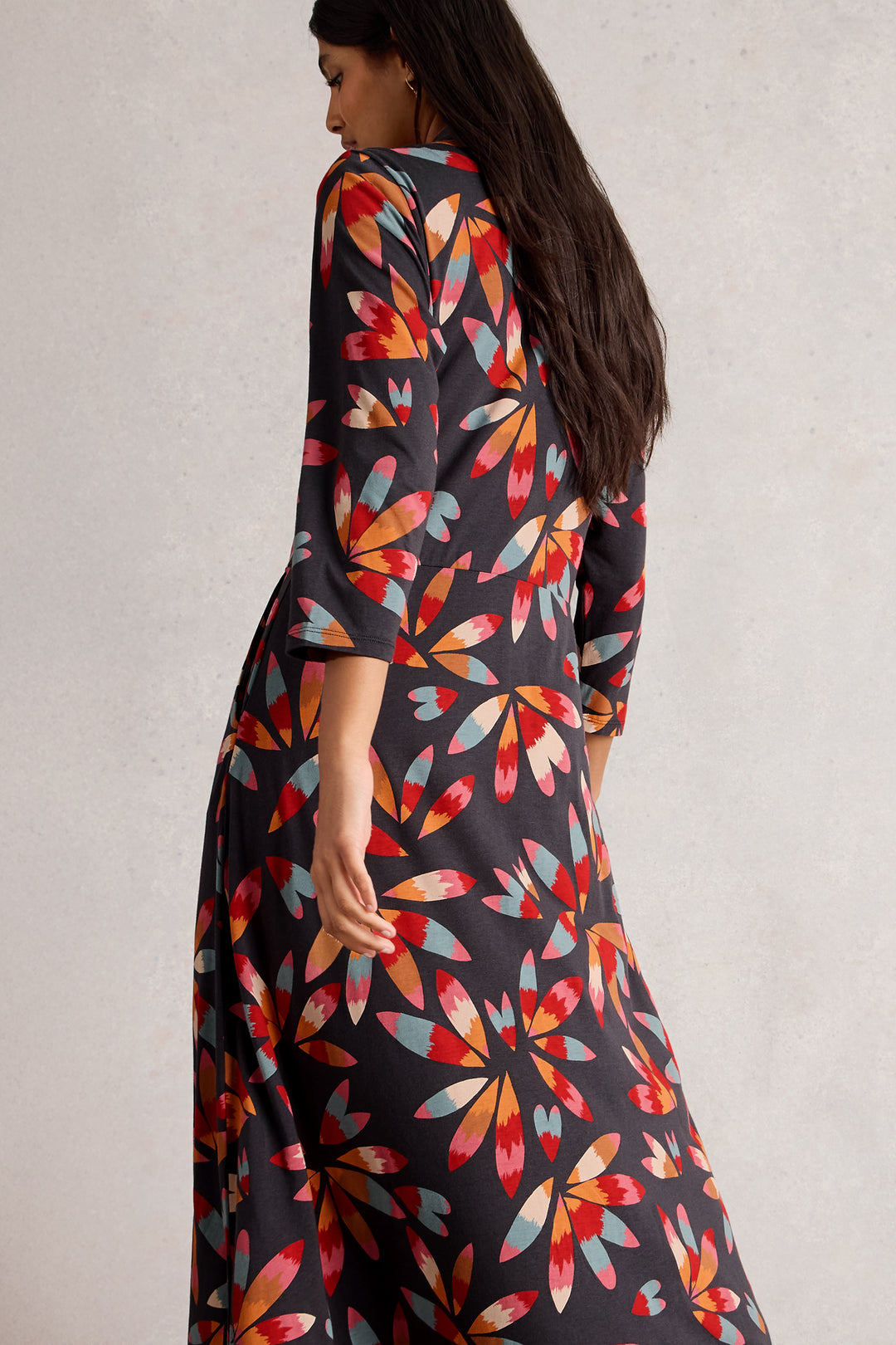 Woman wearing a colorful floral dress with a plain background