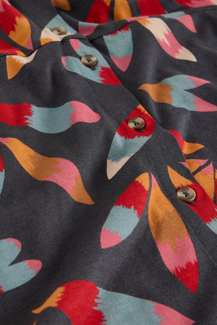 Close-up of a fabric with colorful bird pattern and buttons on a dark background