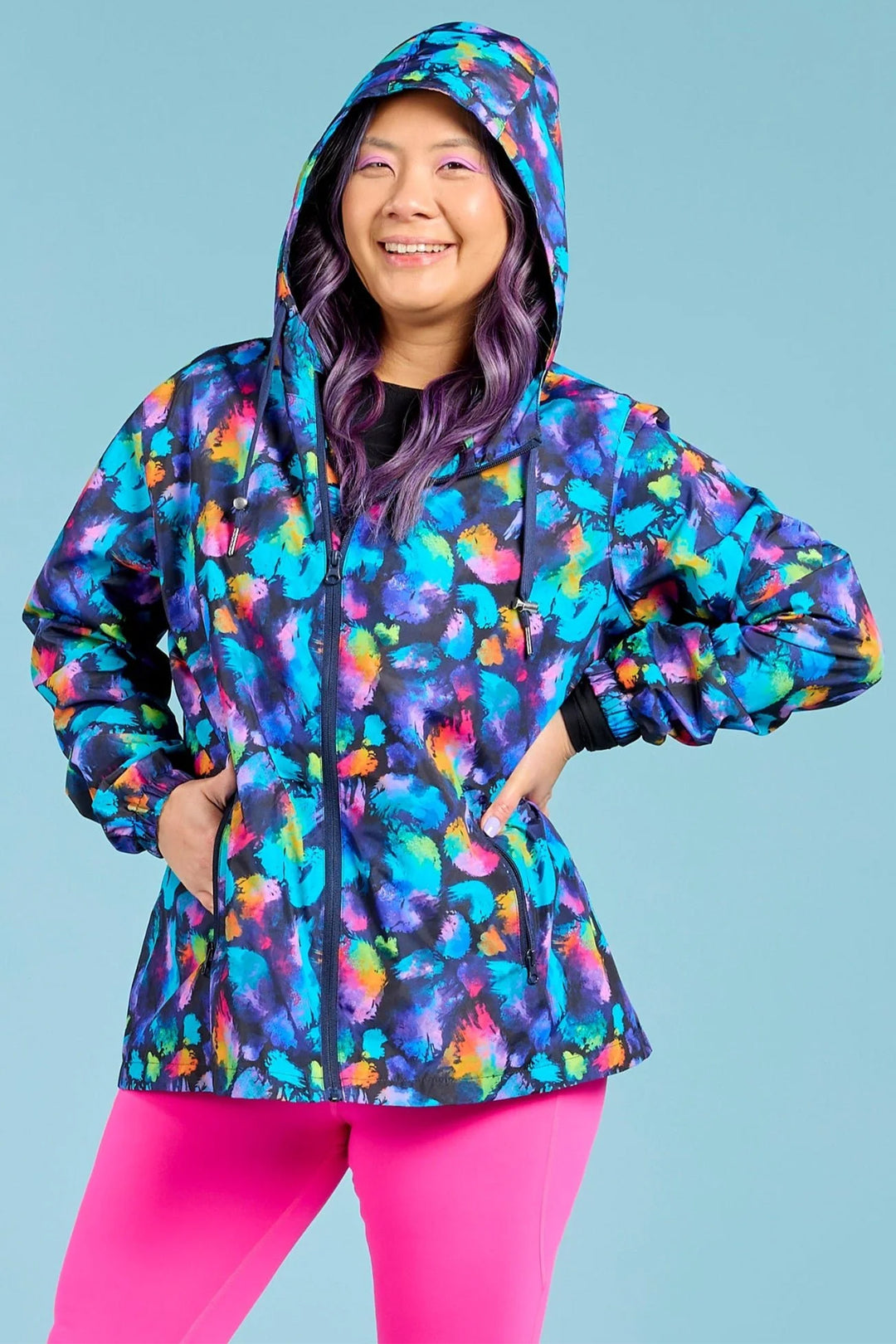 Person wearing a colorful hooded jacket with a blue background