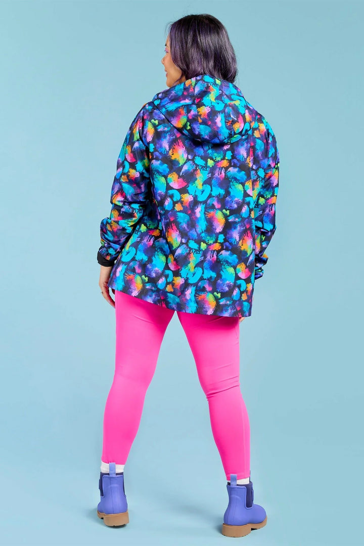 Person wearing a colorful raincoat with pink leggings and blue boots on a light blue background