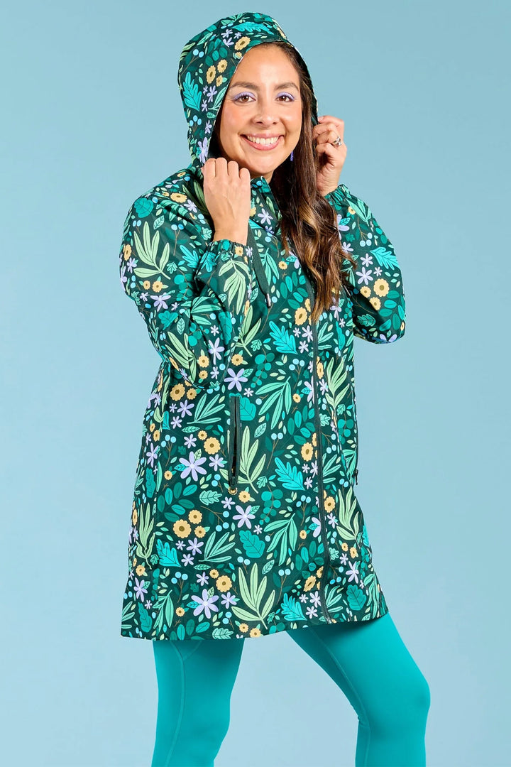 Person wearing a green floral raincoat against a light blue background