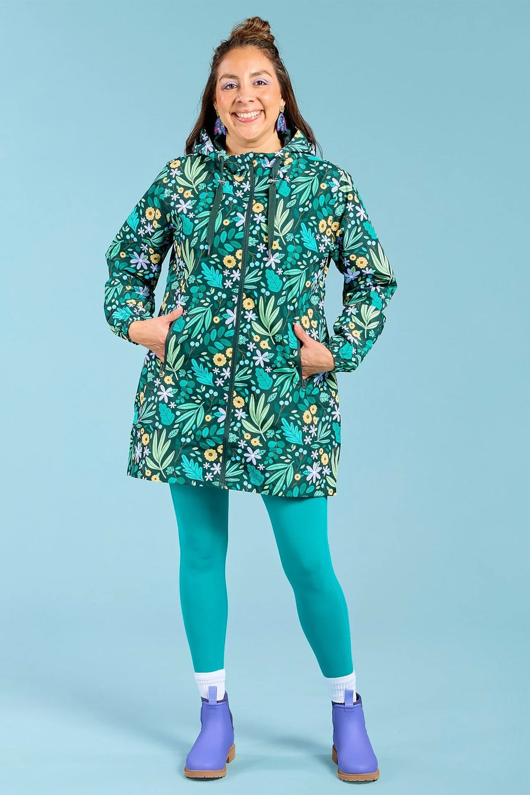 Person wearing a green floral-patterned raincoat on a blue background
