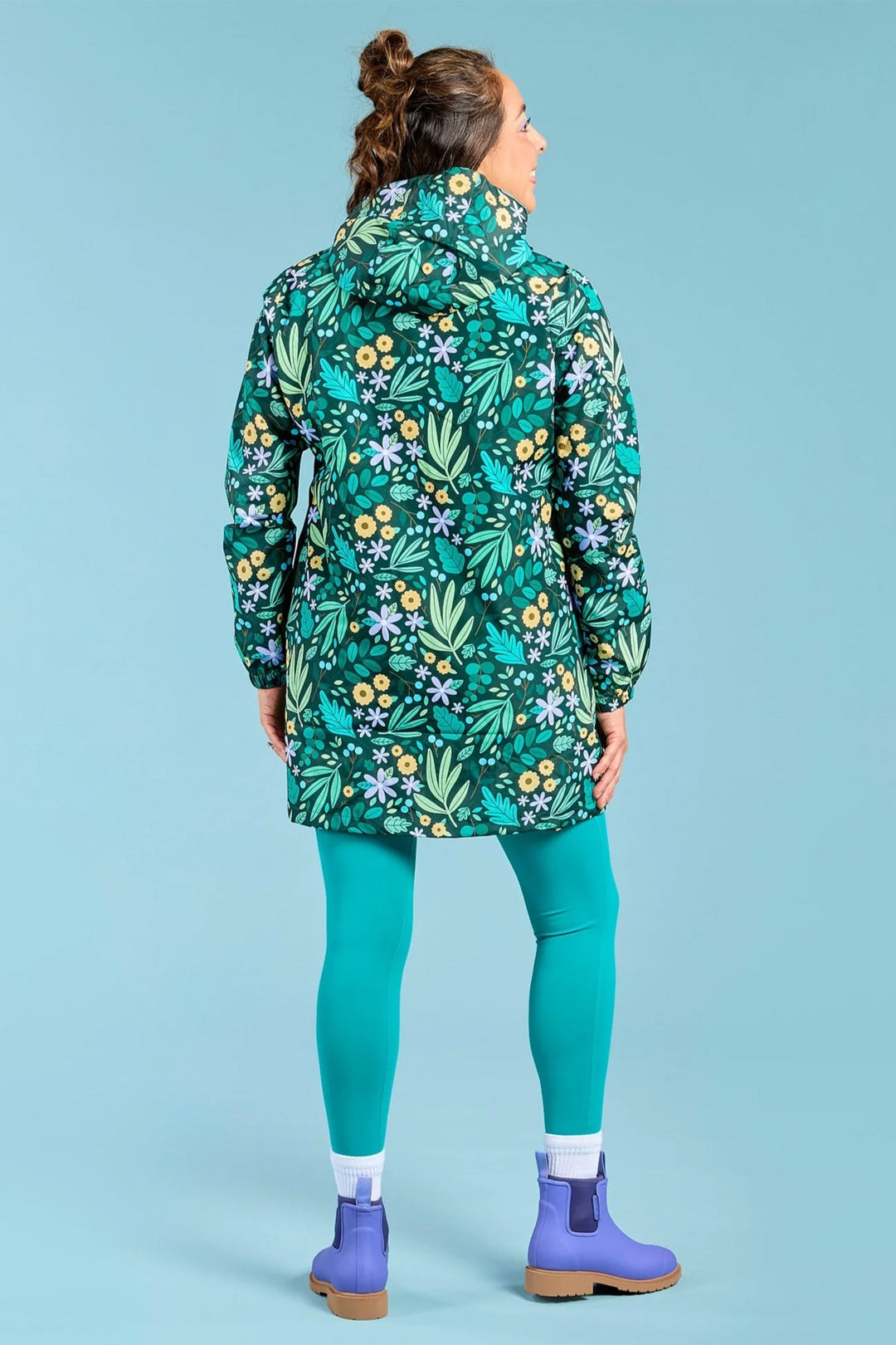 Person wearing a floral-patterned raincoat on a solid blue background
